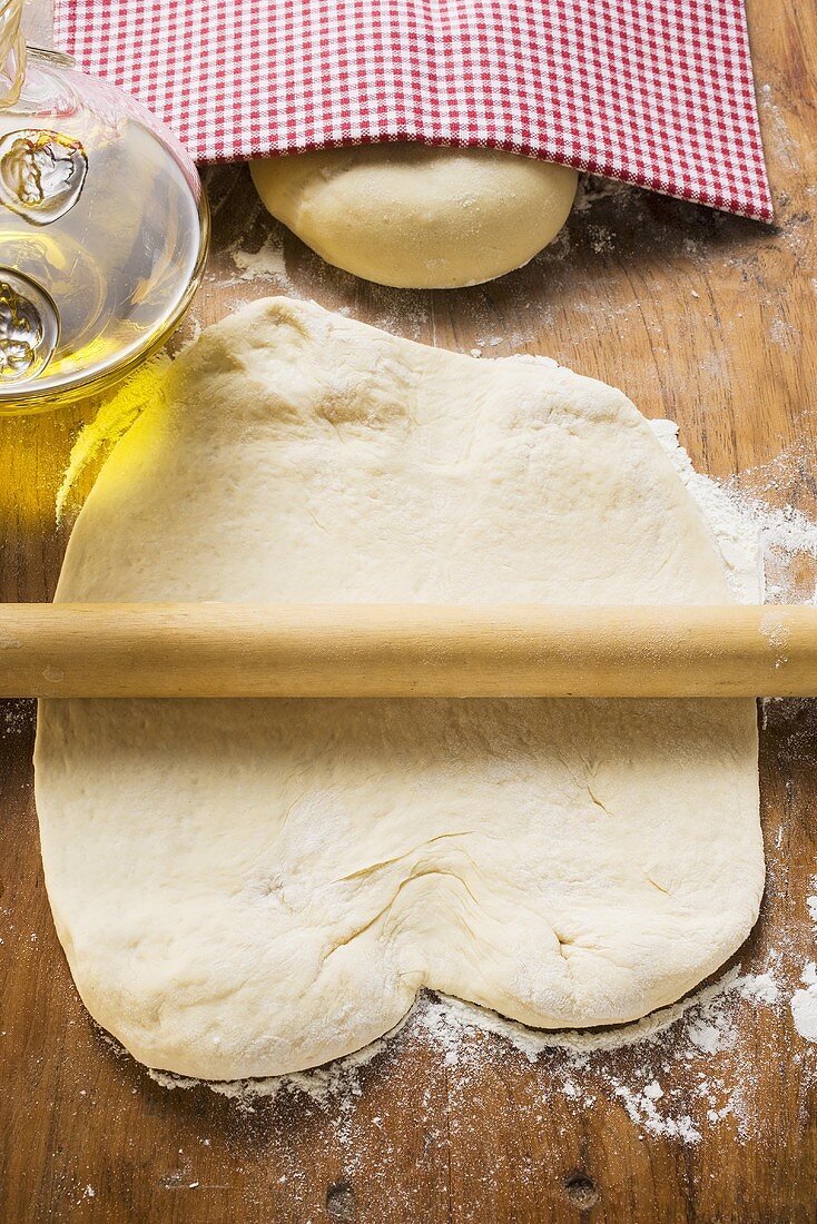 Rolled out dough with rolling pin, ball of dough & olive oil
