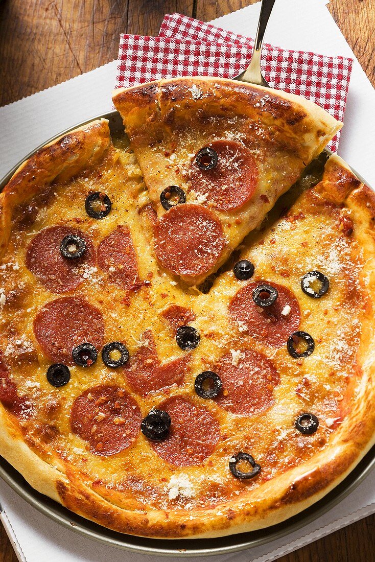 Pizza mit Salami, Käse und Oliven, angeschnitten