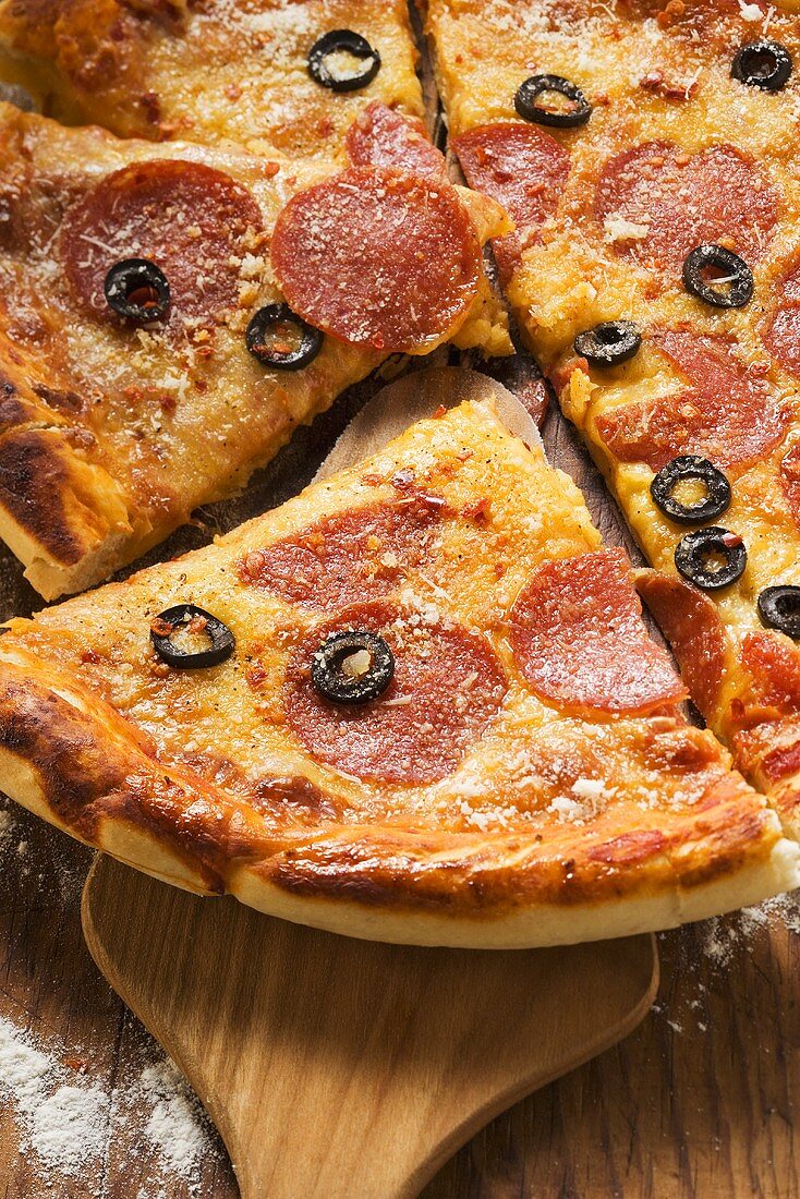 Pizza mit Salami, Käse und Oliven, angeschnitten