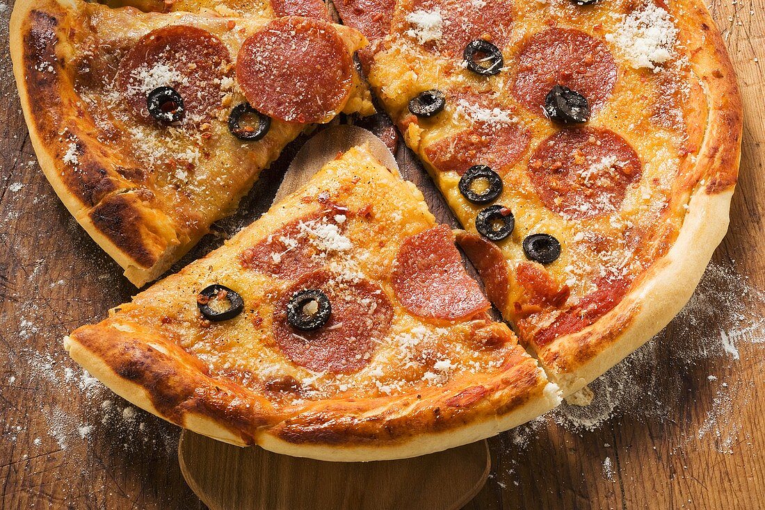 Pizza with salami, cheese and olives, pieces cut