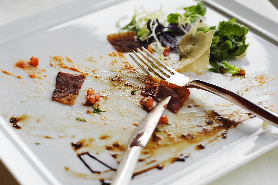 Scraps of food on a plate with cutlery
