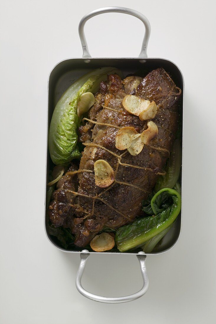 Roast lamb with garlic and vegetables in roasting tin