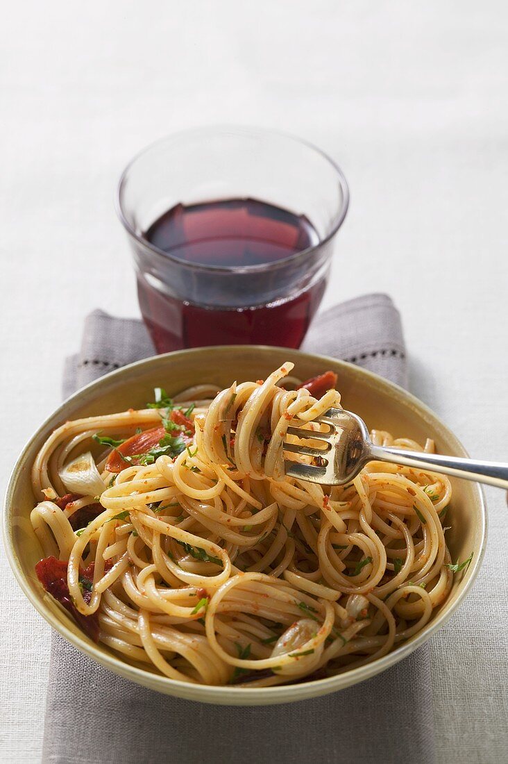 Spaghetti with dried peppers, glass of red wine