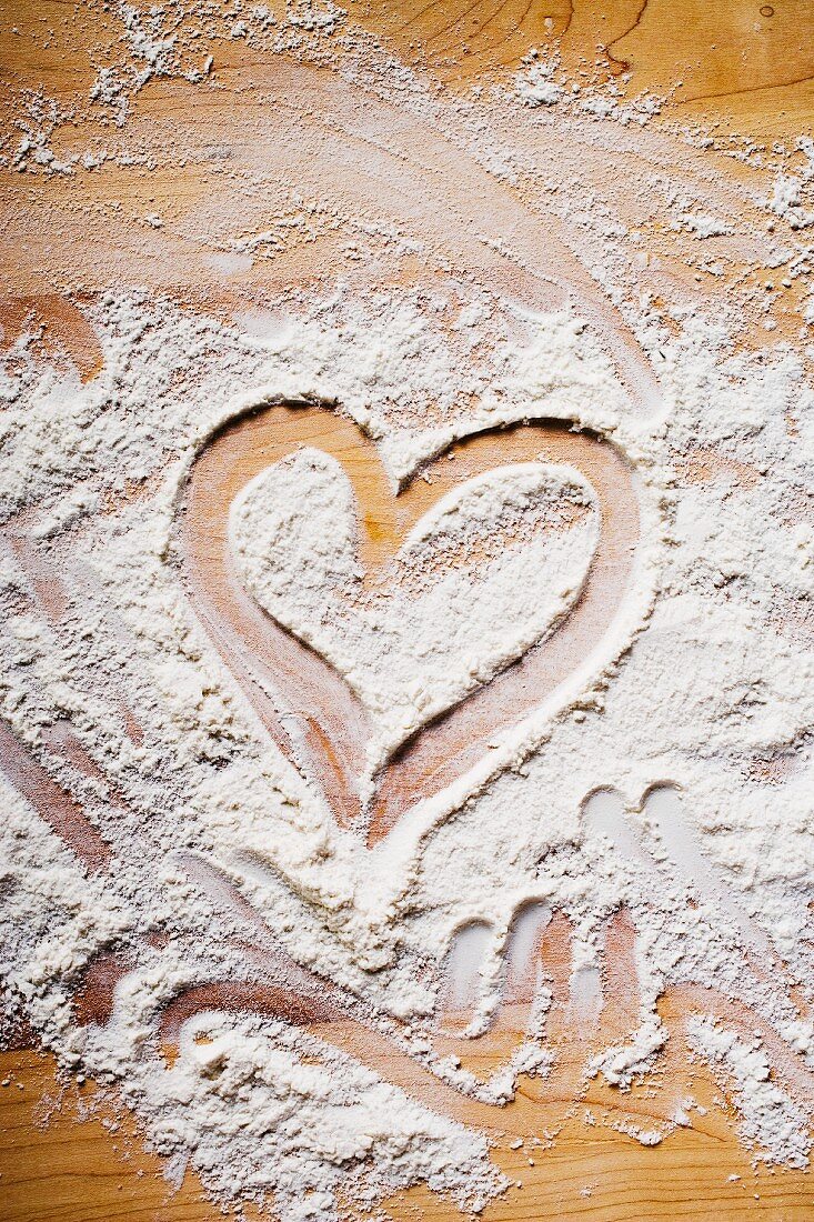 Heart drawn in flour on wooden background