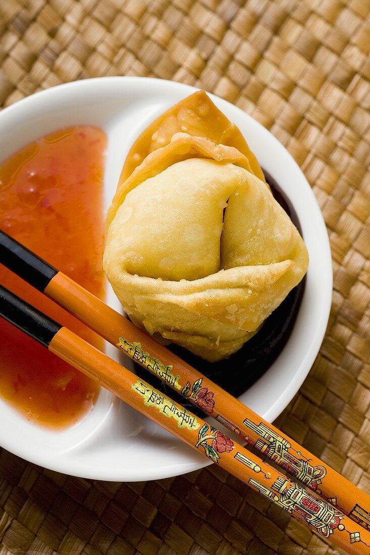 A deep-fried wonton with two sauces (close-up)