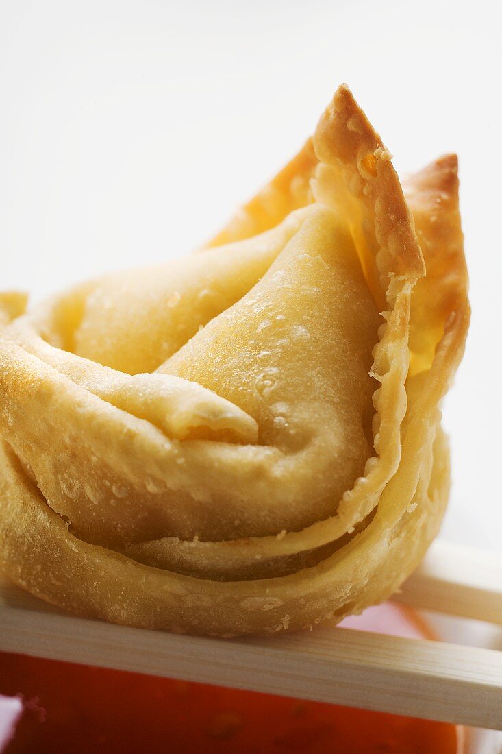 One deep-fried wonton with sweet and sour sauce (close-up)