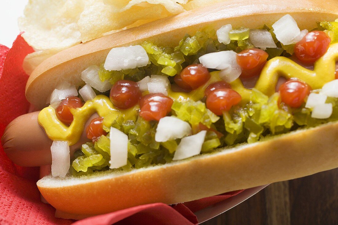 Hot dog with relish, mustard, ketchup, onions and crisps