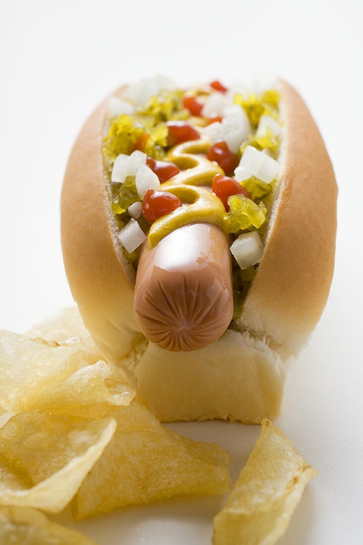 Hot dog with relish, mustard, ketchup, onions and crisps