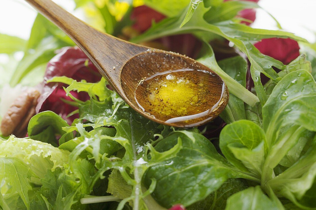 Olivenöl auf Kochlöffel über Blattsalat