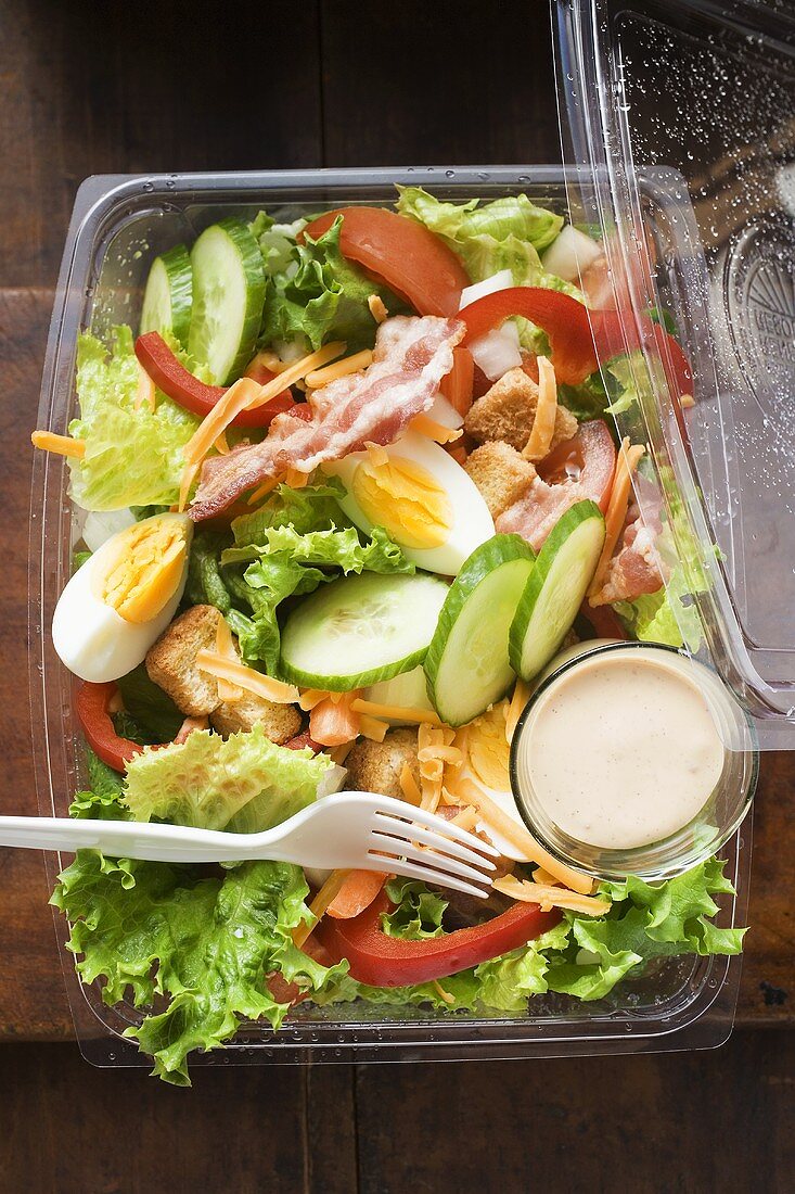 Salad leaves with egg, cheese, bacon and dressing to take away