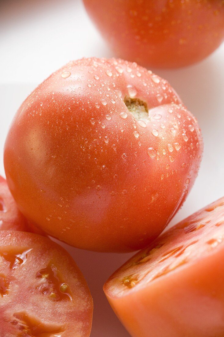 Tomatoes, whole, halved and slices, with drops of water