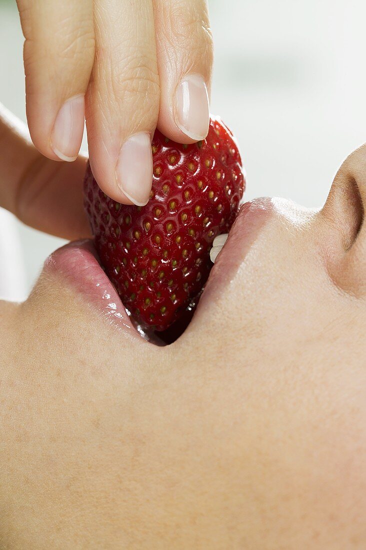 Frau beisst in eine Erdbeere
