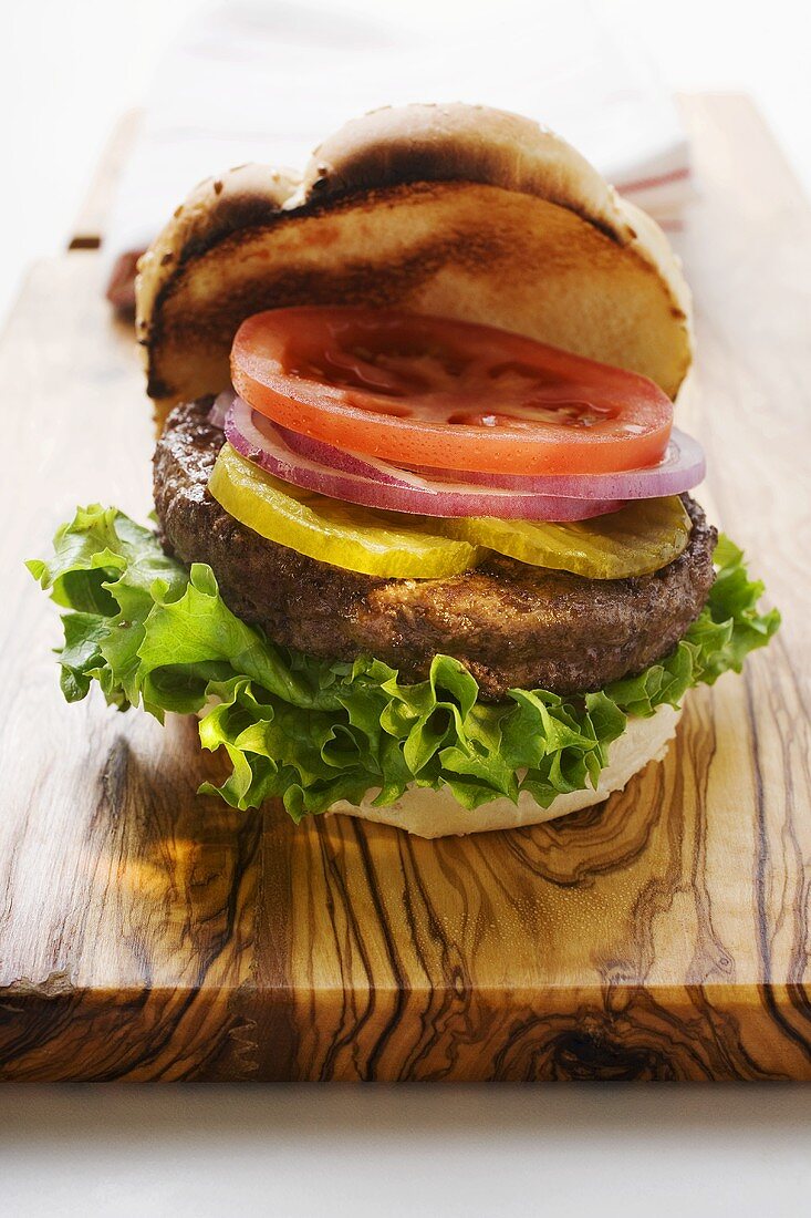 Selbstgemachter Hamburger mit Essiggurken, Zwiebeln, Tomate