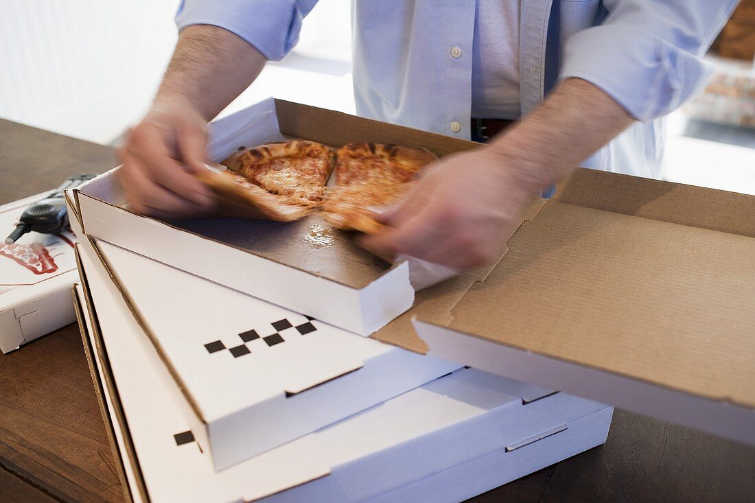 Man dividing up Pizza Margherita in pizza box