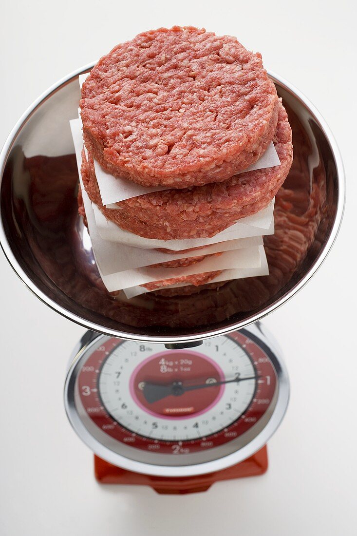 A pile of raw burgers for hamburgers on kitchen scales