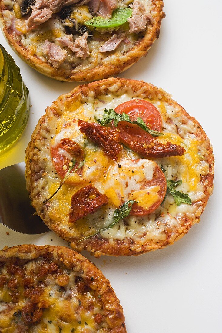 Three different mini-pizzas and bottle of olive oil