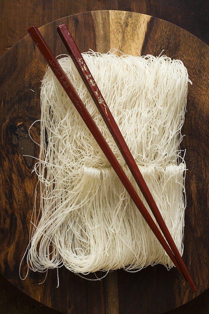 Thin rice noodles on wooden plate with chopsticks