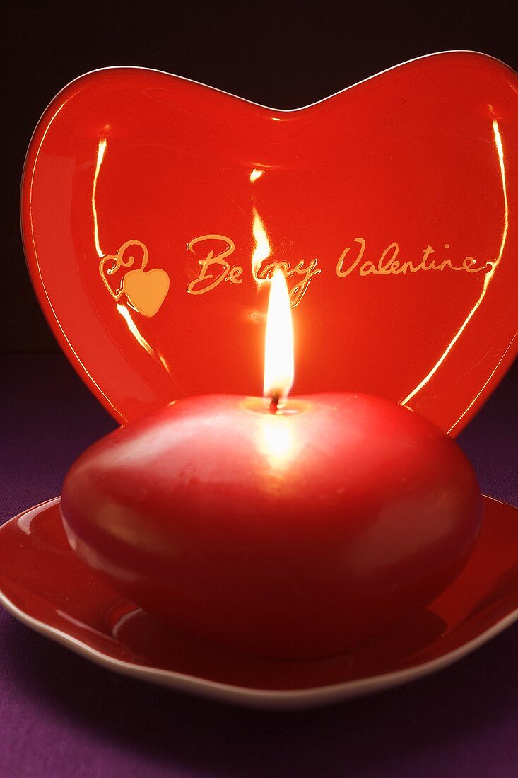 Rote Kerze und herzförmiger Teller für den Valentinstag