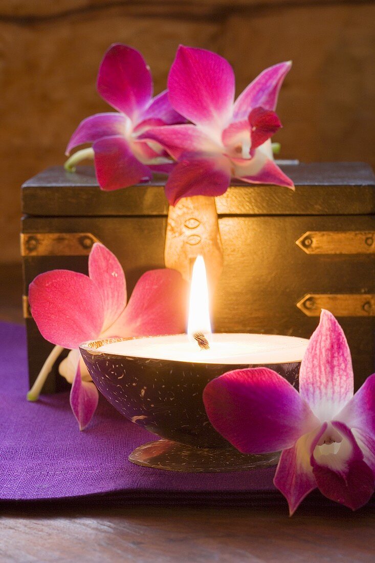 Thailändische Tischdeko: Kerzen, Orchideen, Holzkiste