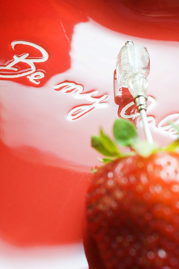 Erdbeere am Spiess auf rotem Teller zum Valentinstag