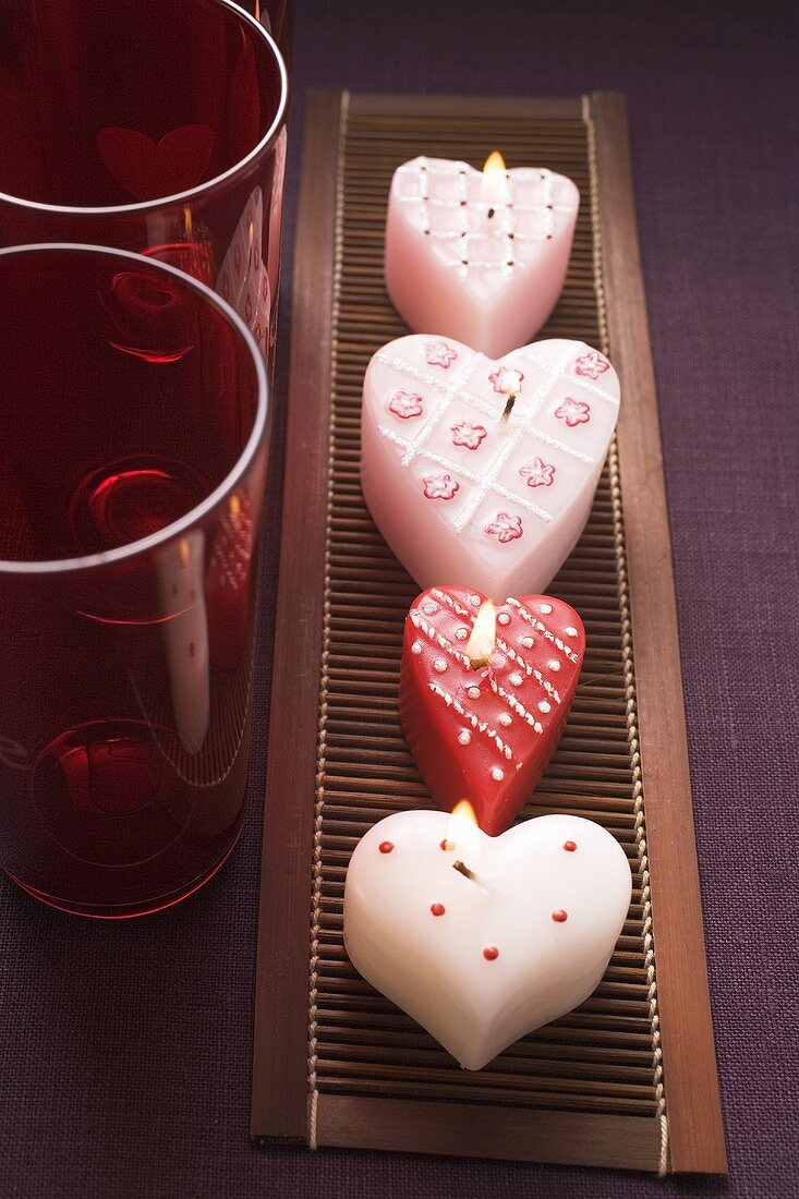 Herzförmige Kerzen und rote Gläser zum Valentinstag