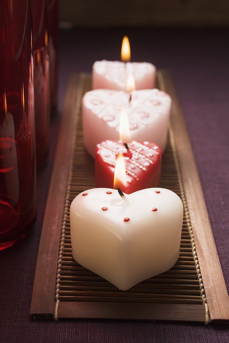 Herzförmige Kerzen und rote Gläser zum Valentinstag