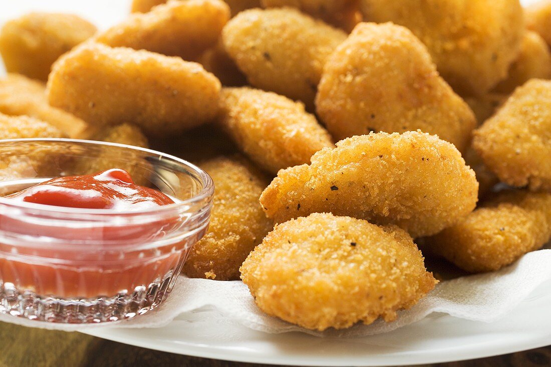 Many chicken nuggets with ketchup on plate