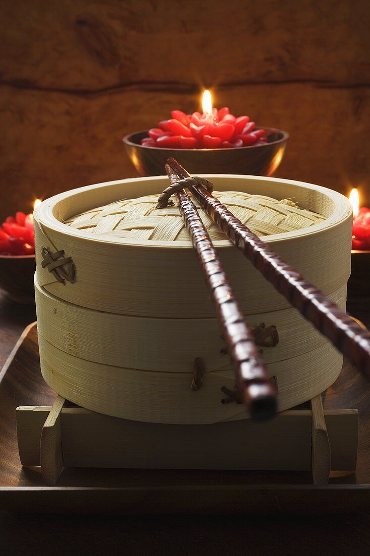 Bamboo steamer in front of burning candles (Asia)