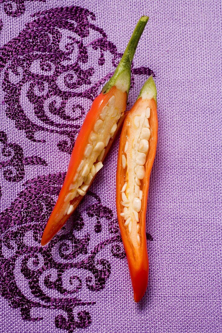 Red chili pepper, halved, on purple fabric