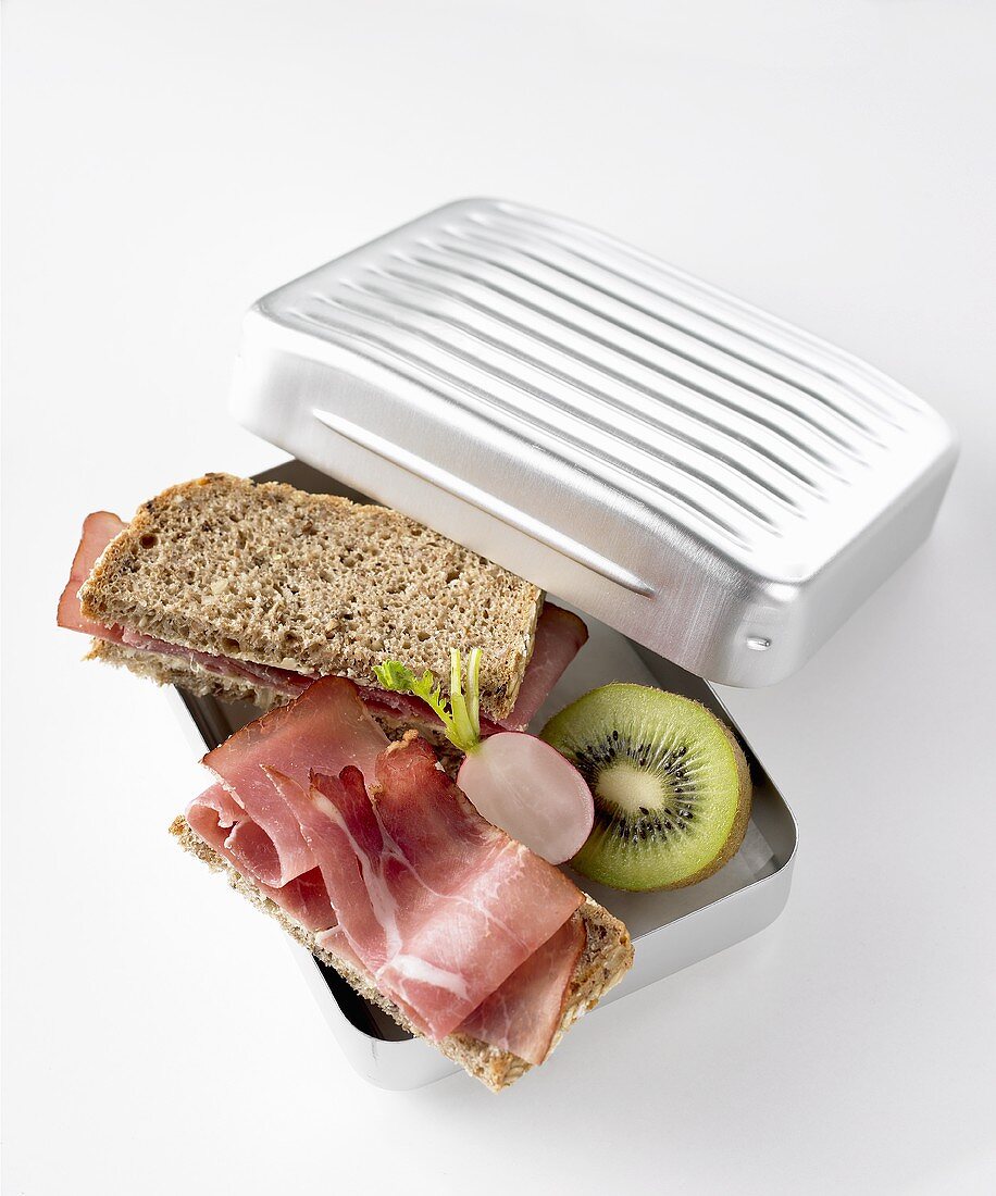 Ham sandwiches, radish and kiwi fruit in lunch box