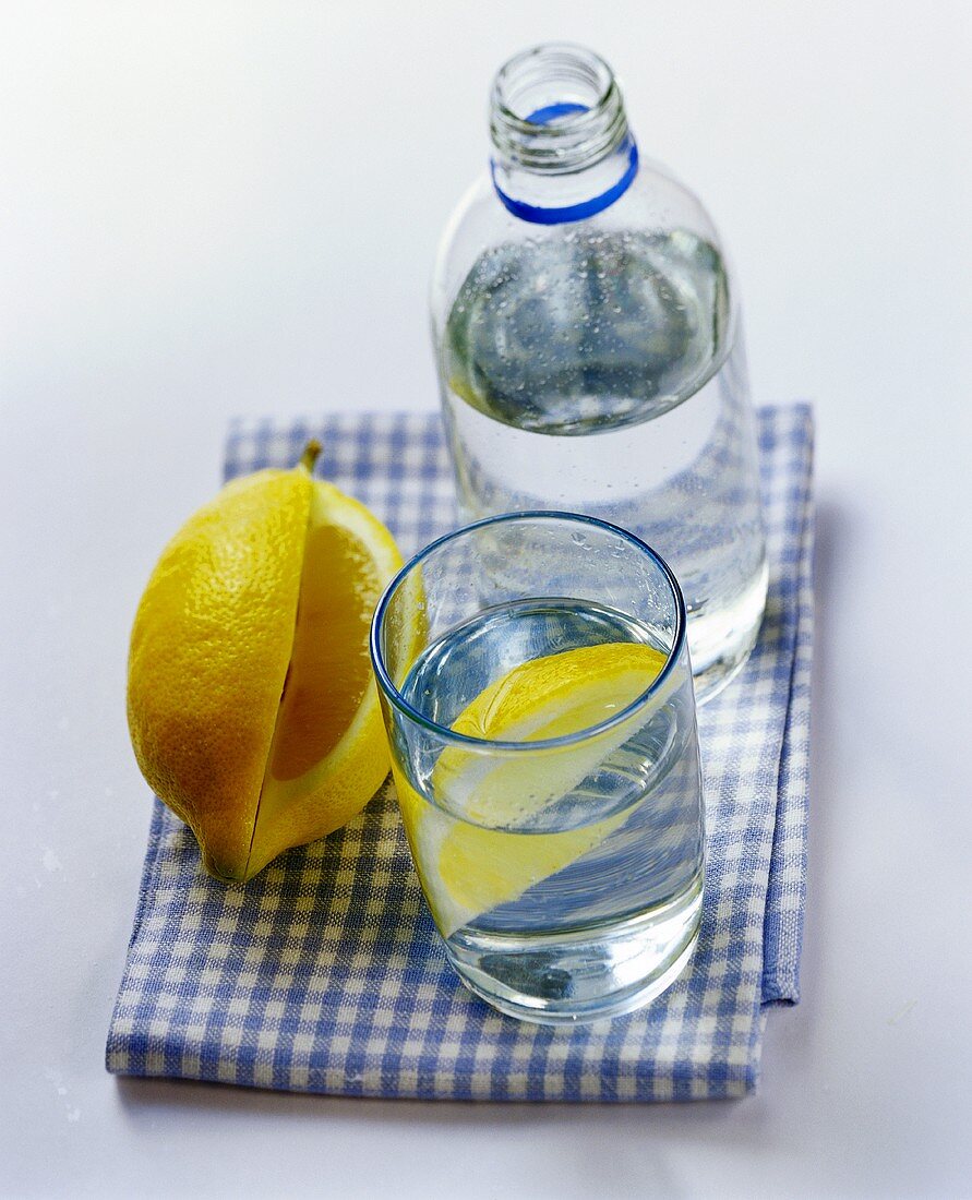 Mineralwasser in Flasche und Glas und angeschnittene Zitrone