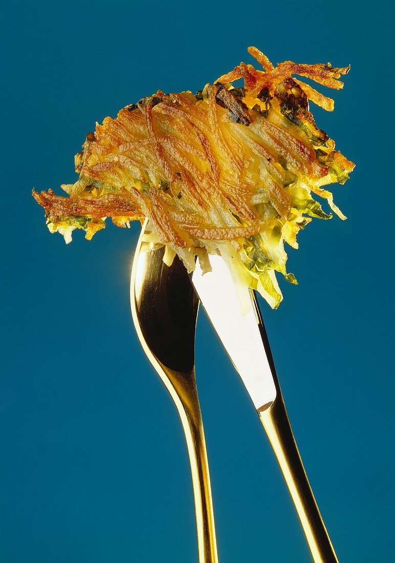A potato rosti on cutlery
