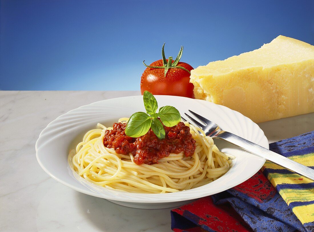 Spaghetti Bolognese, dahinter Tomate und Parmesan