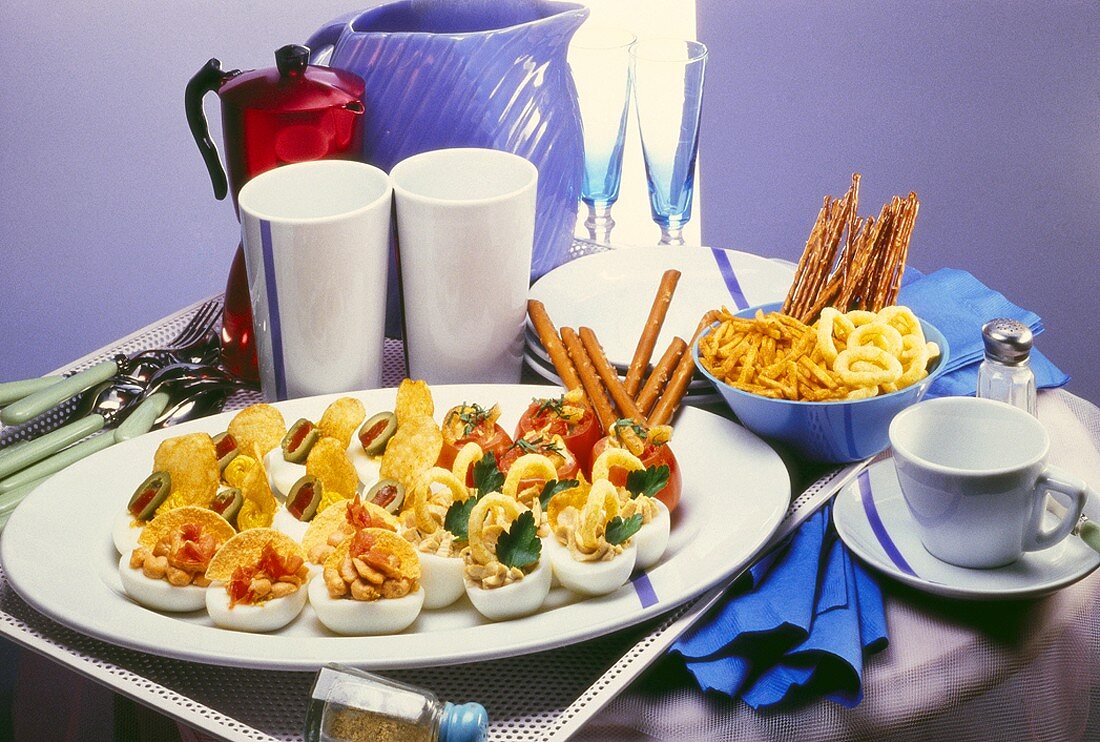 Egg snacks stuffed with nibbles and bowl of nibbles