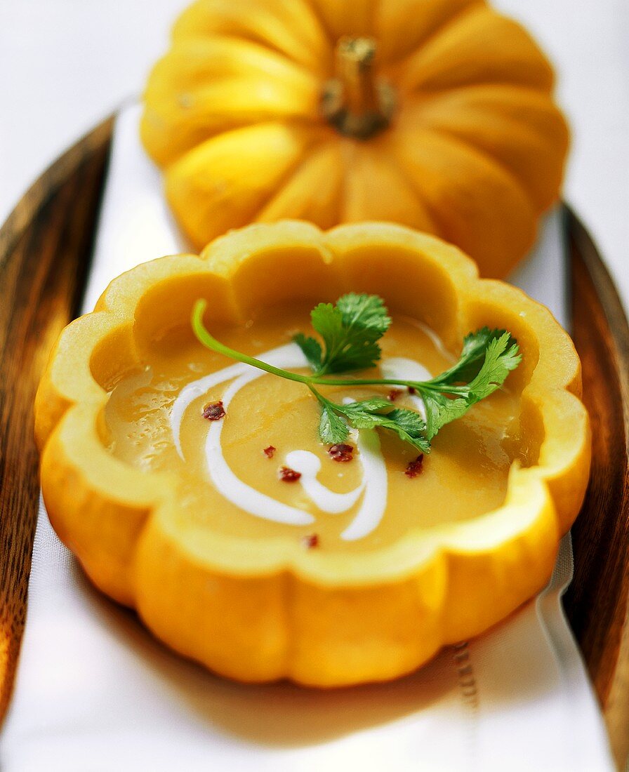 Pumpkin soup with sour cream and coriander served in pumpkin