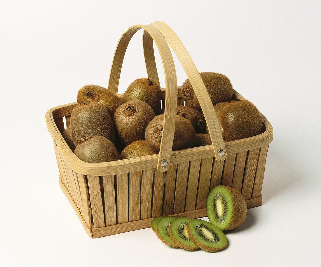 Kiwi fruits in basket with handle, one sliced in front