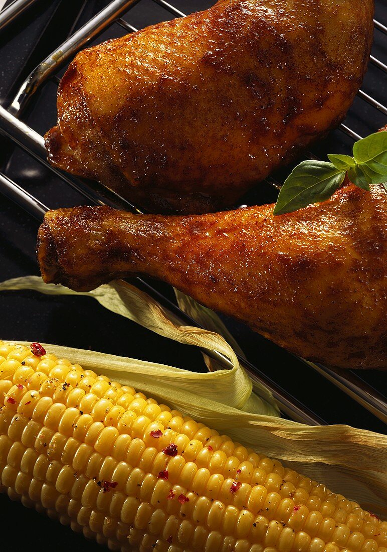 Chicken legs and corn cob on the barbecue