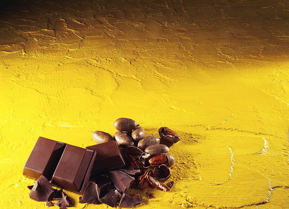 Block of chocolate and pecans against yellow background
