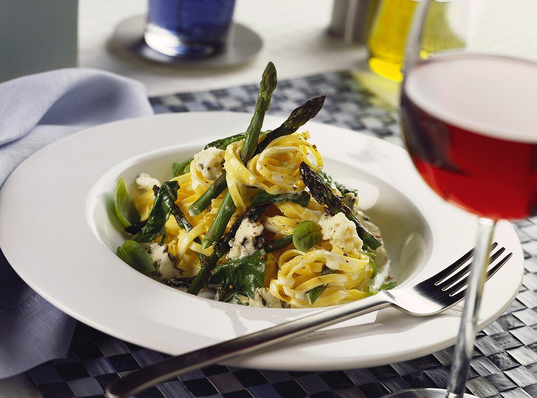 Ribbon pasta on green asparagus & gorgonzola; glass of red wine