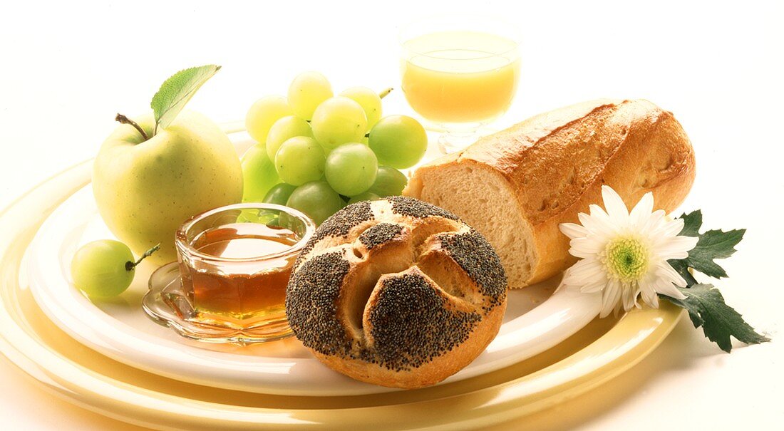 Frühstücksteller mit Brötchen, Baguette, Honig und Obst