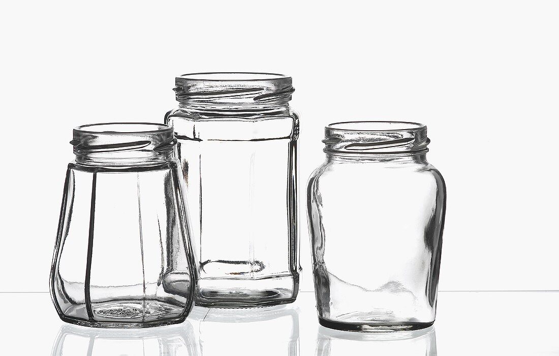 Drei leere Einweckgläser auf einer Glasplatte