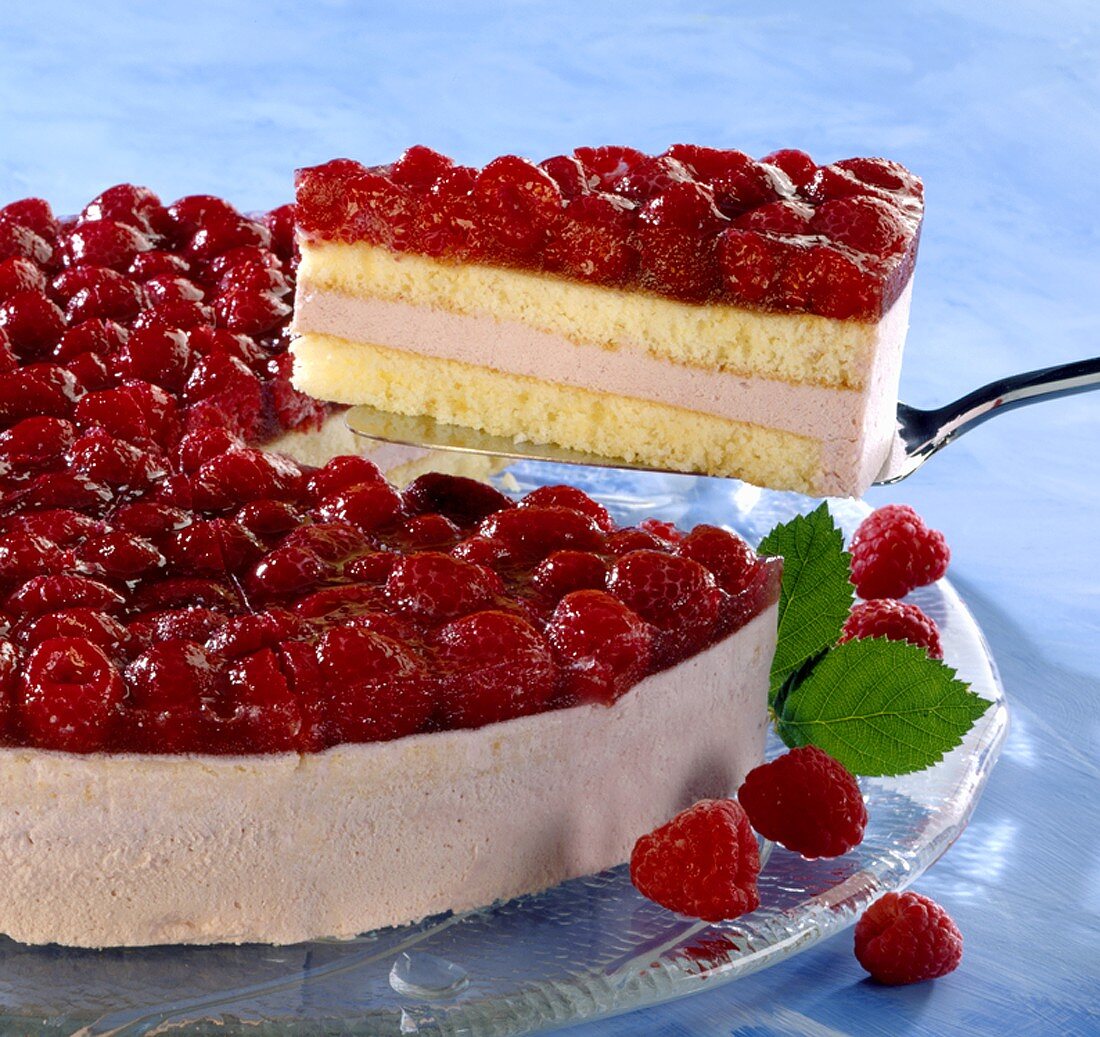 Raspberry cream cake with a piece cut, and a piece of cake