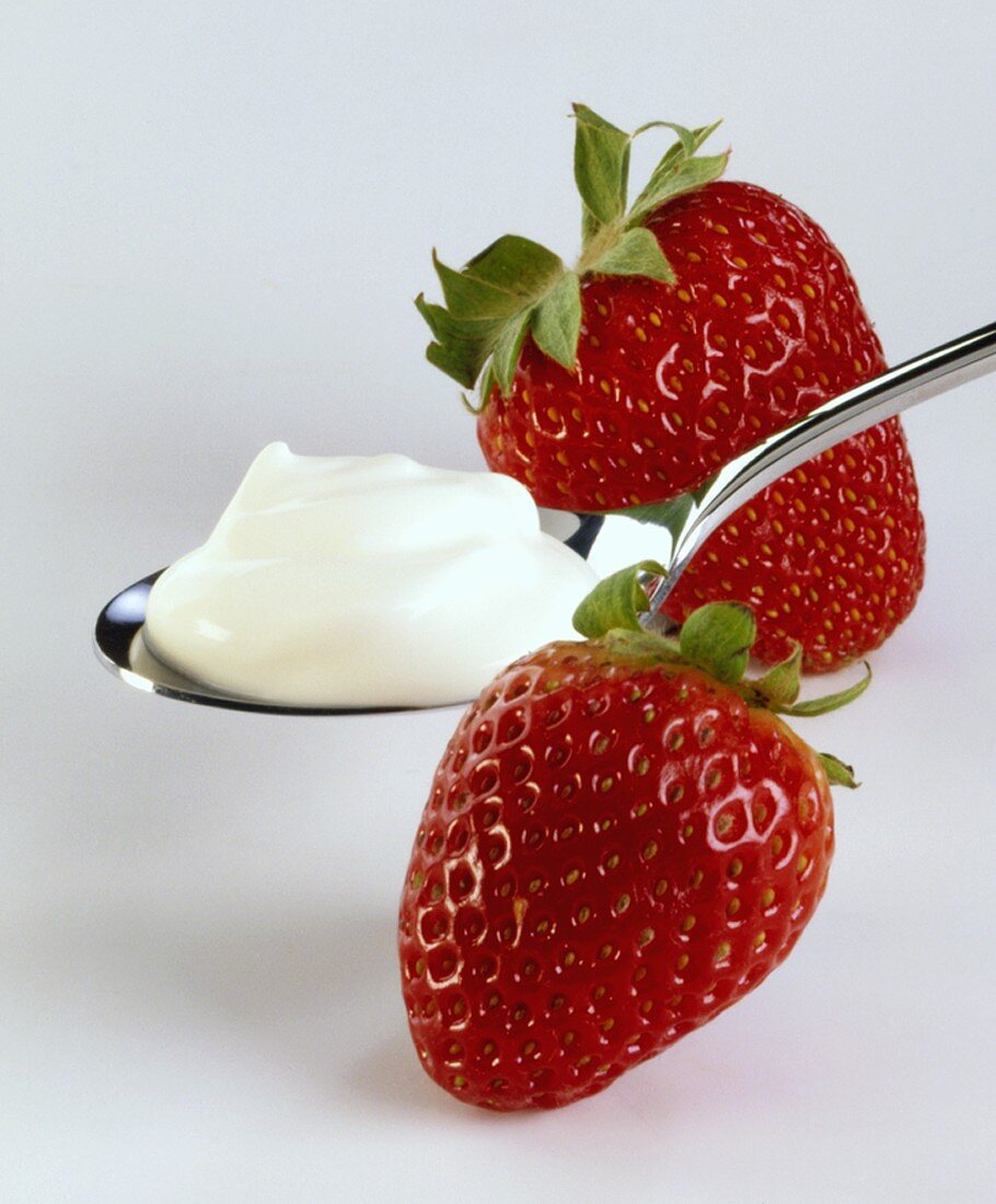 Two strawberries with a spoonful of whipped cream