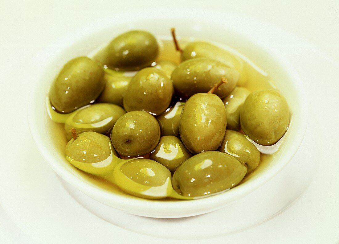 Pickled green olives in a small white bowl