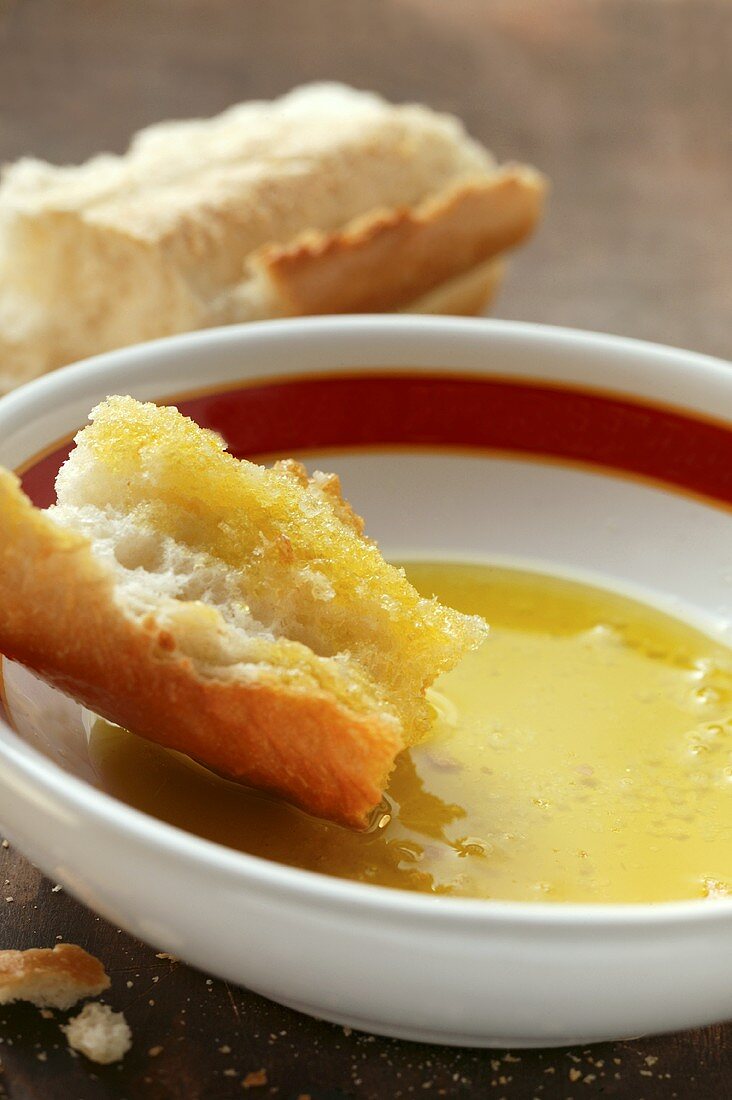 Piece of white bread in a small bowl of olive oil