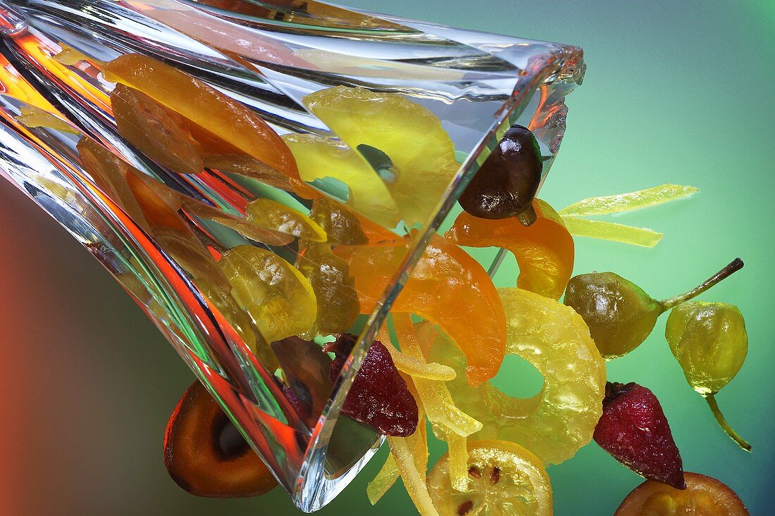 Kandierte Früchte fallen aus einer Glasvase