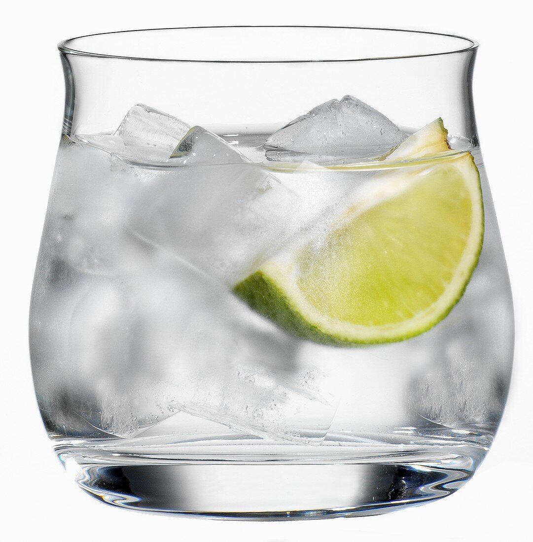 Ein Glas Wasser mit Eiswürfel und einem Limettenschnitz