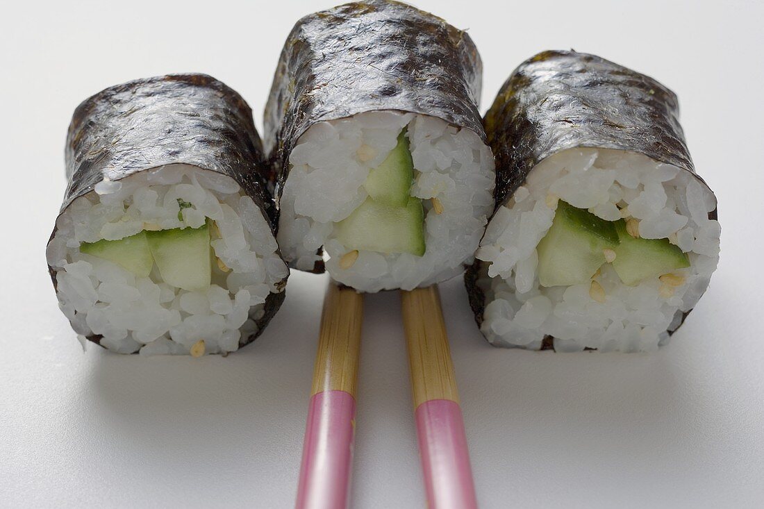 Drei Maki-Sushi mit Gurke und Essstäbchen