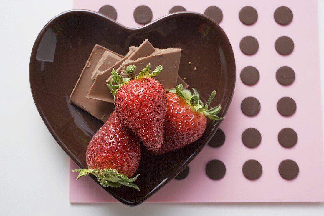 Heart-shaped bowl with chocolate pieces and strawberries