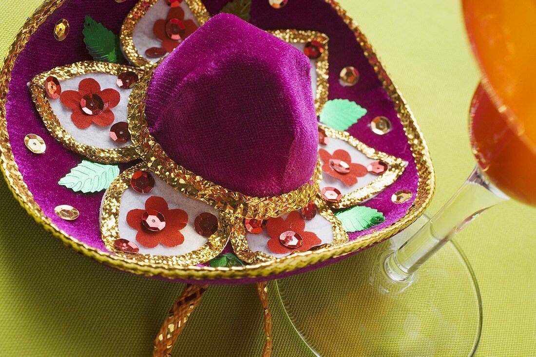Hat embroidered with sequins beside cocktail